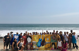 Paint for a Purpose Retreat Event, large group of adults standing in front of the ocean.