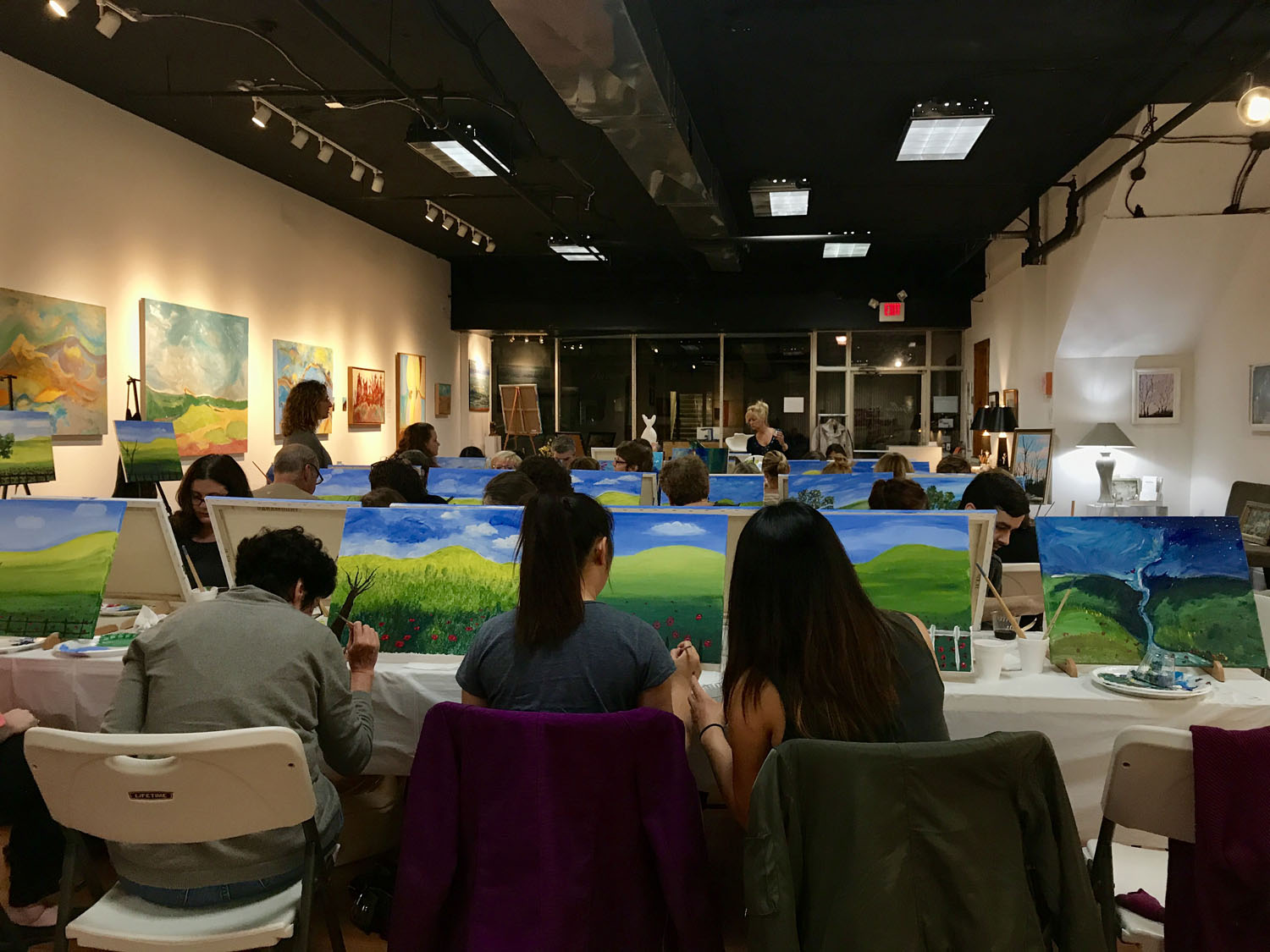 Group of people sitting at tables and painting.