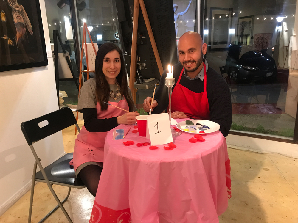 Man and woman sitting at a table with a candle lit in the center.